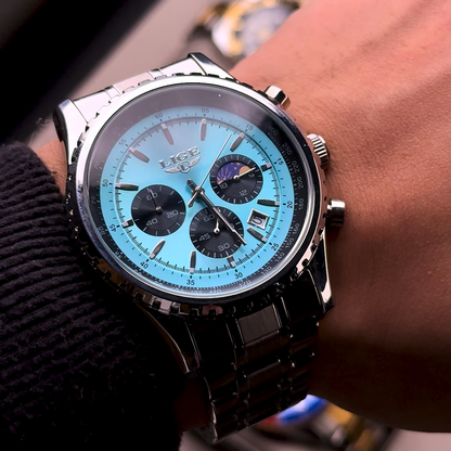 Wrist wearing a watch with a blue face and black strap, blurred background