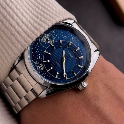 Watch with a blue face and silver strap on a wrist against a neutral background